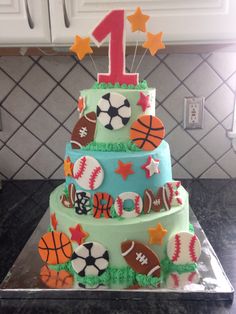 a three tiered cake decorated with sports balls, stars and the number one on top