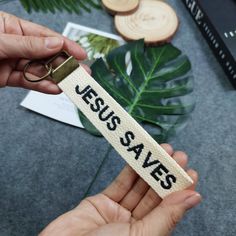 someone holding a keychain that says jesus saves