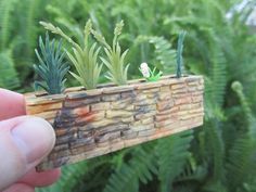 someone is holding up a miniature planter made out of wood and bamboo planks