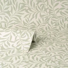 the wall paper is green and white with small leaves on it's surface, as well as a roll of tape