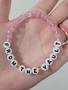 a hand holding a bracelet with beads and letters that spell out the word love on it