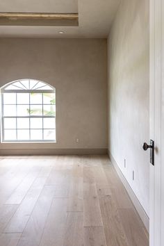 an empty room with wood floors and a window in the wall, looking out to the outside