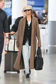 a man and woman walking through an airport with luggage behind them, both carrying bags