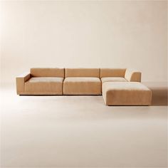 a beige couch sitting on top of a white floor next to a chair and ottoman