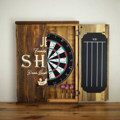 a wooden box with darts and darts inside it on a table next to a wall