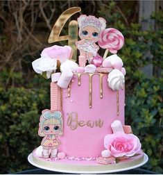 a pink and gold cake decorated with lollipops