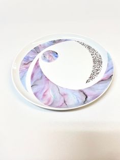 a white plate with a purple and blue design on the side, sitting on a table