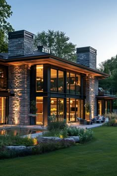 a modern house is lit up at night in the evening with lights shining on it