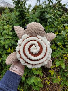 a hand holding a stuffed animal with a spiral in the center