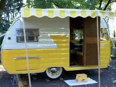 a yellow and white trailer parked next to a tree