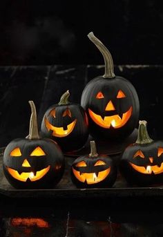 five carved pumpkins with glowing faces on them