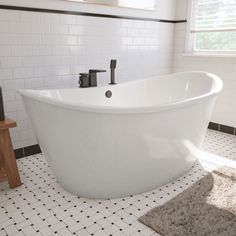 a white bath tub sitting in a bathroom next to a wooden stand with a mirror on it