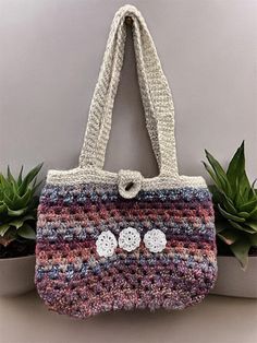 a crocheted handbag with two buttons on the front and one in the back