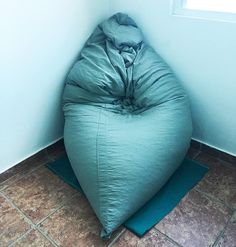 a bean bag chair sitting on top of a blue mat in the corner of a room