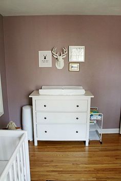 a baby's room with a crib, dresser and pictures on the wall