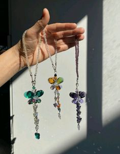 a person holding three different colored necklaces in their hand with the sun shining on them