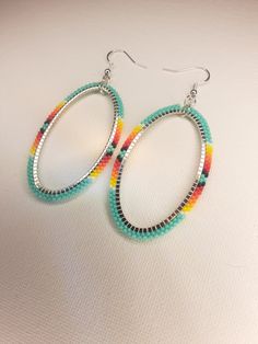 two pairs of hoop earrings with multicolored beads on them sitting on a white surface