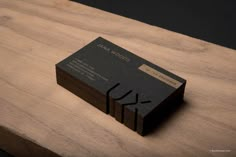 some business cards sitting on top of a wooden table next to a black and white logo