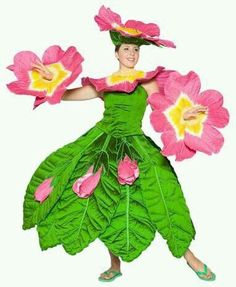 a woman in a green dress with pink flowers on her head and arms, holding two large leaves