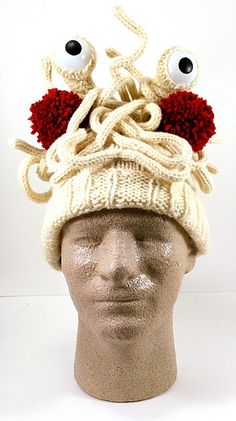 a knitted hat with googly eyes and red balls on it's head