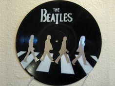 the beatles's logo on a black record with white stripes and people walking across it