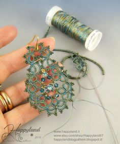 a hand holding a piece of beading next to some thread and spools