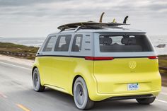 a yellow van driving down the road with surfboards on top