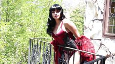 a woman in a red corset and black gloves standing on a balcony railing