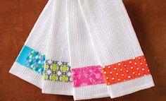 a white towel with colorful patchwork and polka dots hanging on a wooden table top