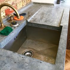 a kitchen sink under a faucet next to a brick wall