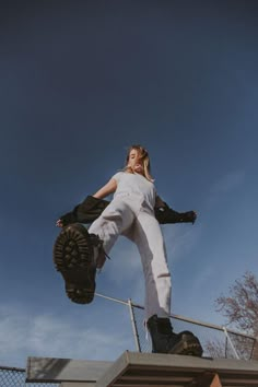 a woman in white jumps up into the air while holding a baseball glove on her hand