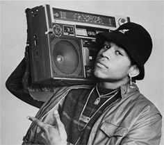 the man is holding an old radio in his right hand and wearing a hat on top of his head