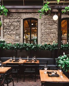 tables and chairs in a restaurant with plants hanging from the ceiling