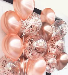 a bunch of pink and gold balloons in the shape of hearts are hanging on a wall