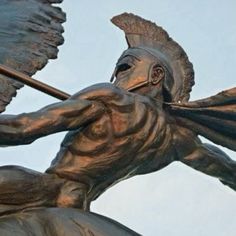 a statue of a man with wings on his back holding a stick in one hand