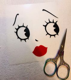 scissors and paper cut out to look like a woman's face with eyelashes on it