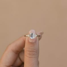 a woman's hand holding an engagement ring with three baguettes on it