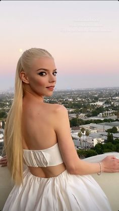 a woman with long blonde hair wearing a white dress and looking off into the distance