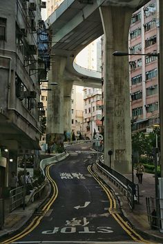 an empty city street with tall buildings in the background and a bridge overhead over it