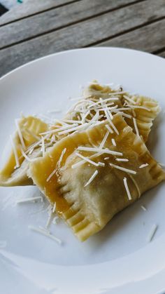 two ravioli with cheese and parmesan on a white plate