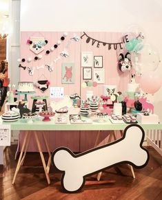 a table topped with lots of cake and desserts next to a dog bone sign