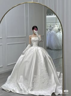 a woman in a white wedding dress looking at herself in the mirror with her hand on her face