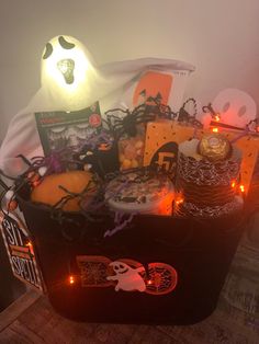 a basket filled with lots of halloween treats on top of a table next to candles