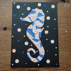 a seahorse made out of paper on a wooden table with polka dots and circles