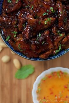 a blue bowl filled with meat and sauce next to a small white bowl on top of a wooden table