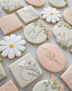 some decorated cookies are on a table with flowers and words painted on them in pastel colors