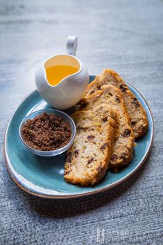 a blue plate topped with crackers next to a cup of tea and powdered sugar