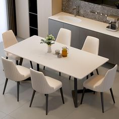 a dining room table with white chairs and a tv mounted on the wall above it