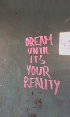 graffiti written on the side of a building reads dream until it's your reality