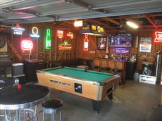 a man cave with pool tables and neon signs